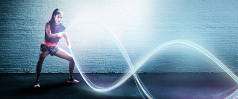 Glasfaser von envia TEL Eine Frau beim Rope Training, wobei die Seile durch leuchtende digitale Stränge dargestellt sind