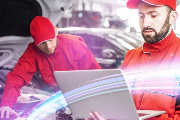 Glasfaserverbindung in Werkstatt & Autohaus enviaTEL KFZ-Mechatroniker arbeitet mit Laptop und envia-TEL-Glasfaserverbindung