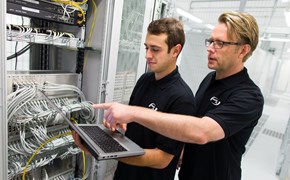 enManaged-Datacenter-Servicekatalog enviaTEL Zwei Mitarbeiter der envia TEL mit einem Laptop in der Hand, im Datacenter vor Blades