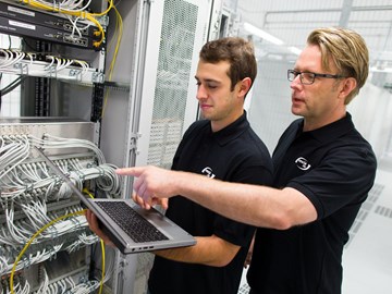 enManaged-Datacenter-Servicekatalog enviaTEL Zwei Mitarbeiter der envia TEL mit einem Laptop in der Hand, im Datacenter vor Blades