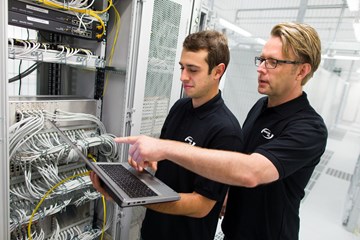 enManaged-Datacenter-Servicekatalog enviaTEL Zwei Mitarbeiter der envia TEL mit einem Laptop in der Hand, im Datacenter vor Blades
