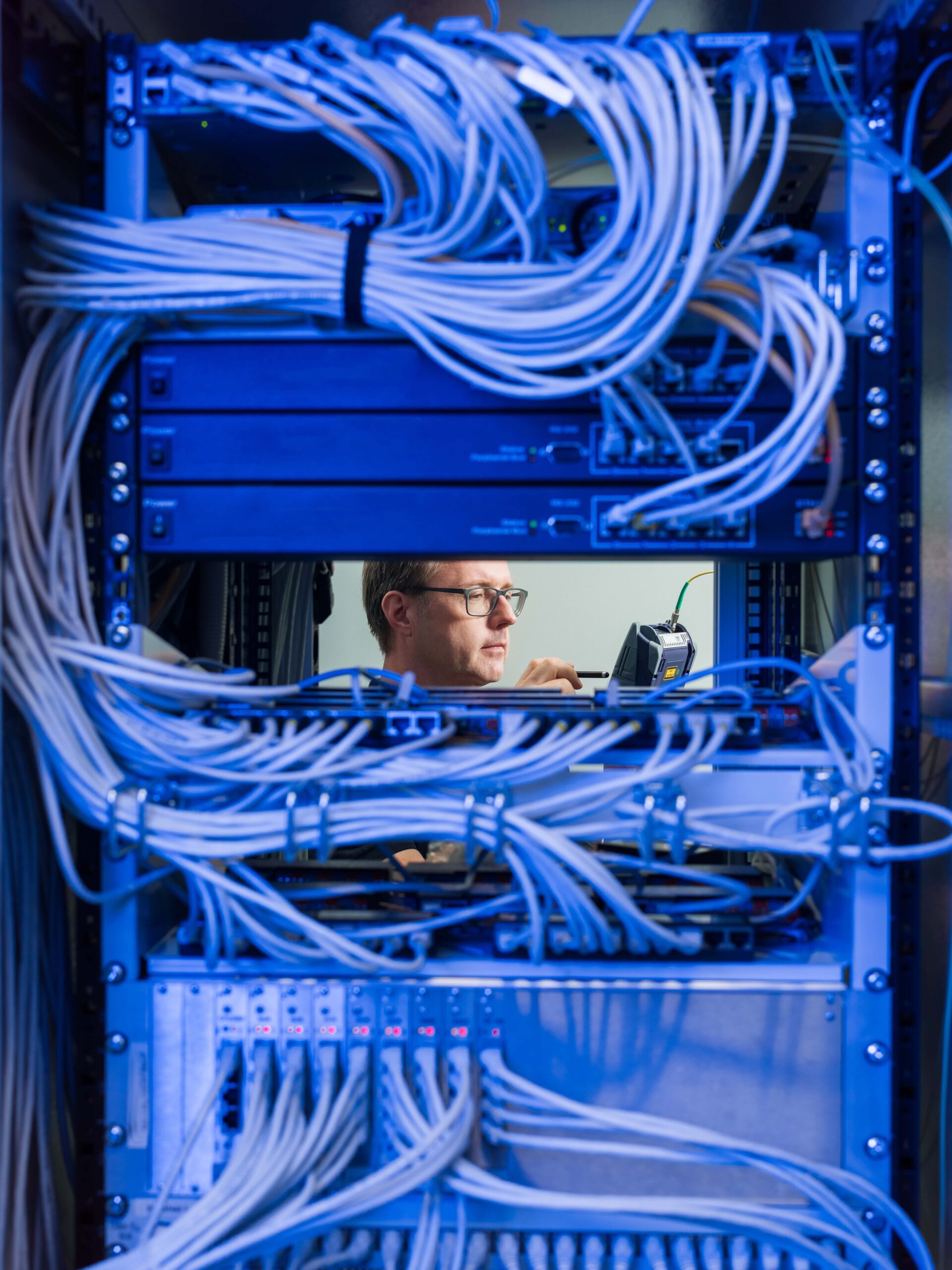 Großes Rack im Datacenter Leipzig, eine Blade entnommen, durch die Lücke ist Datacenter-Experte der envia TEL zu sehen
