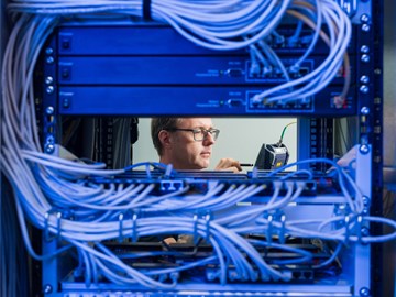 envia-TEL_DE-CIX-Leipzig_Datacenter-Experte Großes Rack im Datacenter Leipzig, eine Blade entnommen, durch die Lücke ist Datacenter-Experte der envia TEL zu sehen