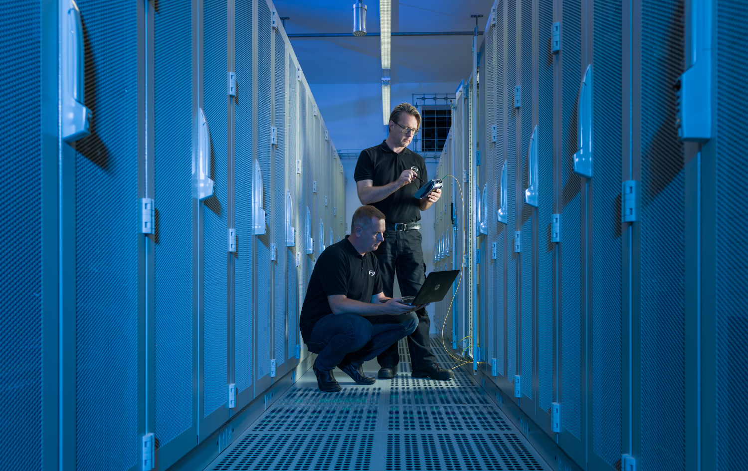 IT Techniker im Datacenter vor Serverschränken