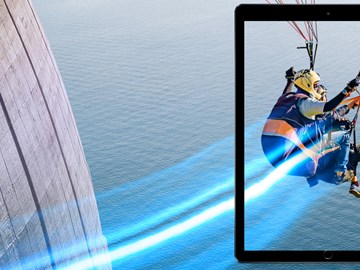 Next Generation Firewalls Zwei Personen fliegen mit einem Gleitschirm vor einer Staumauer