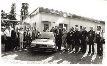 AHC-Gruppe historische Aufnahme Schwarz-Weiß-Aufnahme mit Mitarbeitern der AHC-Gruppe, die neben einem Auto stehen