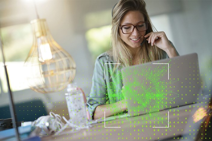 Sicher arbeiten im Homeoffice Frau arbeitet mit Laptop im Homeoffice. Grafik im Vordergrund deutet potentielle Bedrohung an.