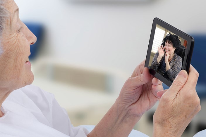 Surfen vom Krankenbett aus Ältere Dame liegt im Krankenbett und tätigt einen Videoanruf über ihr Telefon