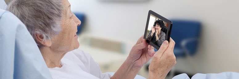 Surfen vom Krankenbett aus Ältere Dame liegt im Krankenbett und tätigt einen Videoanruf über ihr Telefon