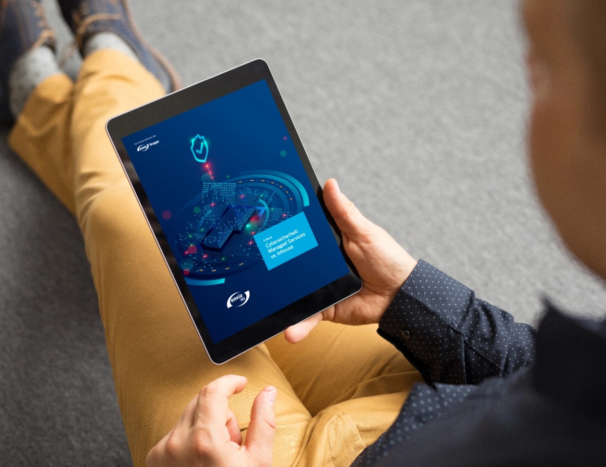 Ein Mann sitzt auf dem Boden, hält ein E-Book in der Hand und liest den Bericht zur Cybersicherheit der envia TEL
