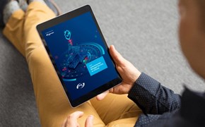 Whitepaper ebook Firewall Selbst oder Service Ein Mann sitzt auf dem Boden, hält ein E-Book in der Hand und liest den Bericht zur Cybersicherheit der envia TEL