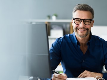 Security-Newsletter enviaTEL Mann im Büro lächelt in die Kamera