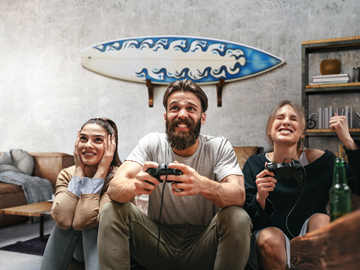 Highspeed-Internet für zu Hause Drei junge Menschen sitzen im Wohnzimmer und spielen begeistert ein Videospiel