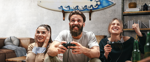 Highspeed-Internet für zu Hause Drei junge Menschen sitzen im Wohnzimmer und spielen begeistert ein Videospiel