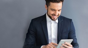 enviaTEL Newsletter bestellen Lächelnder Mann im Anzug liest envia TEL Newsletter auf dem Tablet