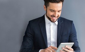 enviaTEL Newsletter bestellen Lächelnder Mann im Anzug liest envia TEL Newsletter auf dem Tablet