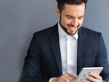 enviaTEL Newsletter bestellen Lächelnder Mann im Anzug liest envia TEL Newsletter auf dem Tablet