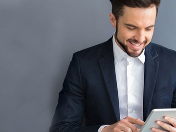 enviaTEL Newsletter bestellen Lächelnder Mann im Anzug liest envia TEL Newsletter auf dem Tablet