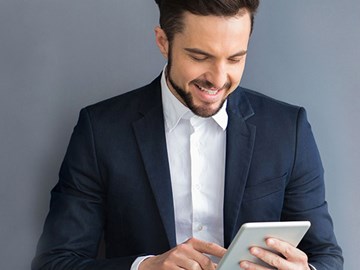 enviaTEL Newsletter bestellen Lächelnder Mann im Anzug liest envia TEL Newsletter auf dem Tablet