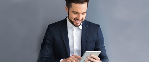 enviaTEL Newsletter bestellen Lächelnder Mann im Anzug liest envia TEL Newsletter auf dem Tablet