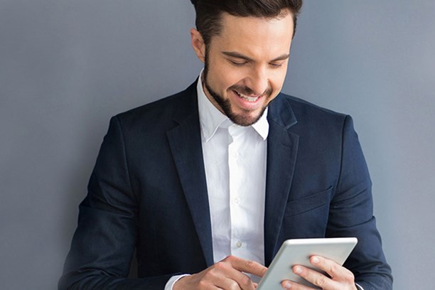 enviaTEL Newsletter bestellen Lächelnder Mann im Anzug liest envia TEL Newsletter auf dem Tablet