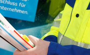 Glasfaserbau-Unternehmen-Produkte-envia-TEL Arbeiter hält Glasfaserstrang auf Baustelle vor envia TEL Werbeplakat