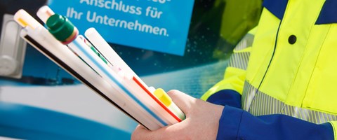 Glasfaserbau-Unternehmen-Produkte-envia-TEL Arbeiter hält Glasfaserstrang auf Baustelle vor envia TEL Werbeplakat