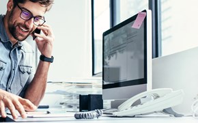 VoIP für Unternehmen Mann sitzt am Schreibtisch und telefoniert