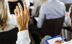 Die nächsten Infoveranstaltungen Mann hebt linke Hand für Wortmeldung während einer Veranstaltung