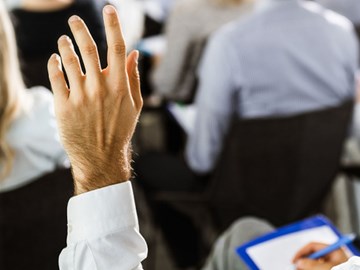 Die nächsten Infoveranstaltungen Mann hebt linke Hand für Wortmeldung während einer Veranstaltung