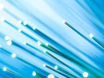 Die Vorteile von Glasfaser gegenüber Kupfer Bündel leuchtender Glasfasern vor einem blauen Hintergrund.