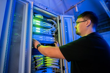 Werkstudentenjob bei der envia TEL Auszubildender bei der Arbeit vor einem Serverschrank