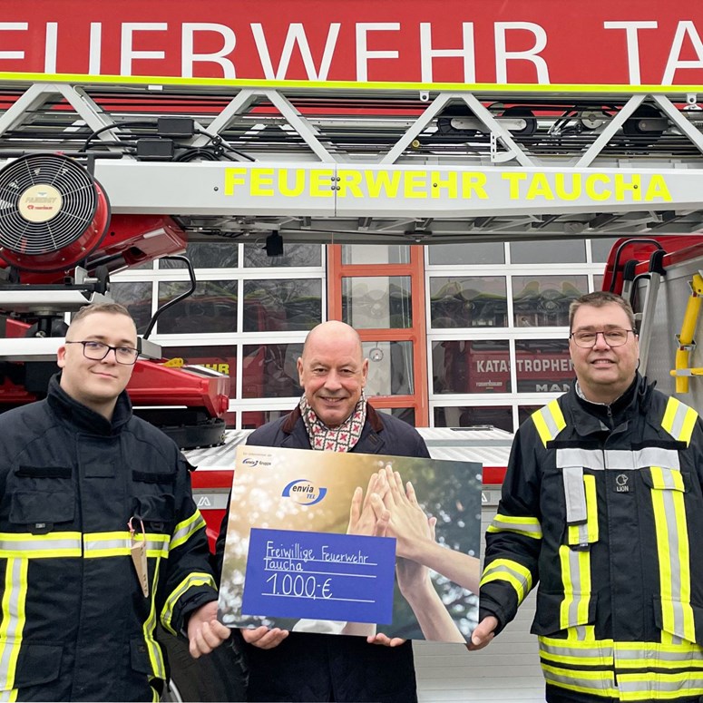 Jugendfeuerwehr Taucha mit Stephan Drescher der envia TEL Stephan Drescher, Geschäftsführer der envia TEL, steht mit Feuerwehrmännern vor der Feuerwache in Taucha und hält einen Scheck in der Hand